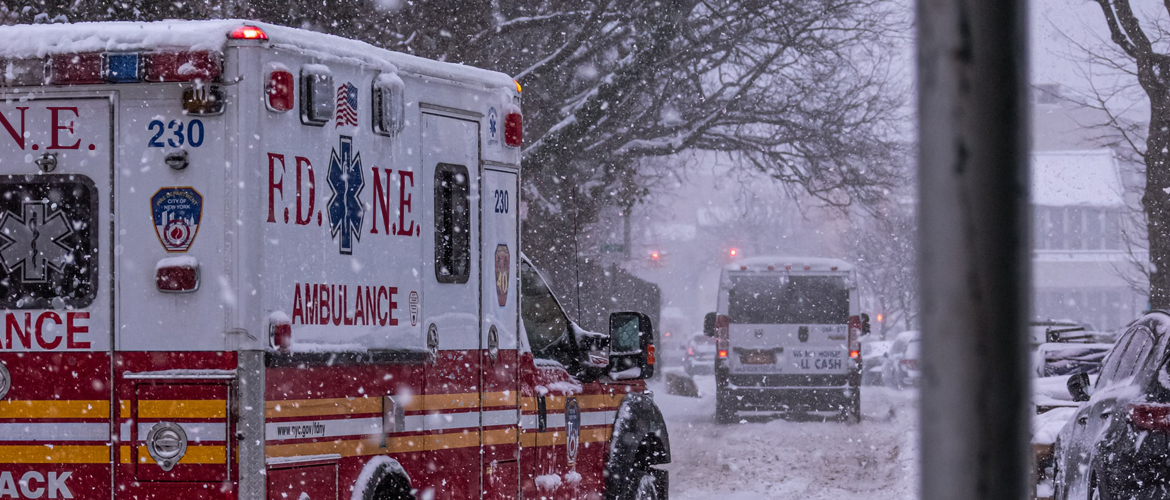 An ambulance driving down the street in the snow.