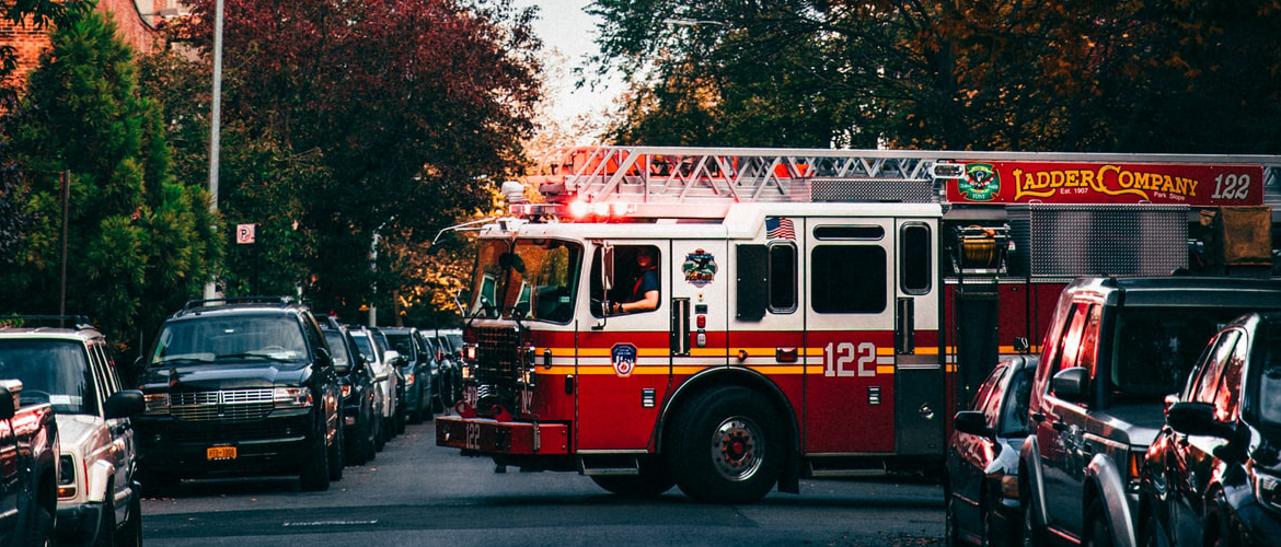 A firetruck in a neighborhood turning down the street.