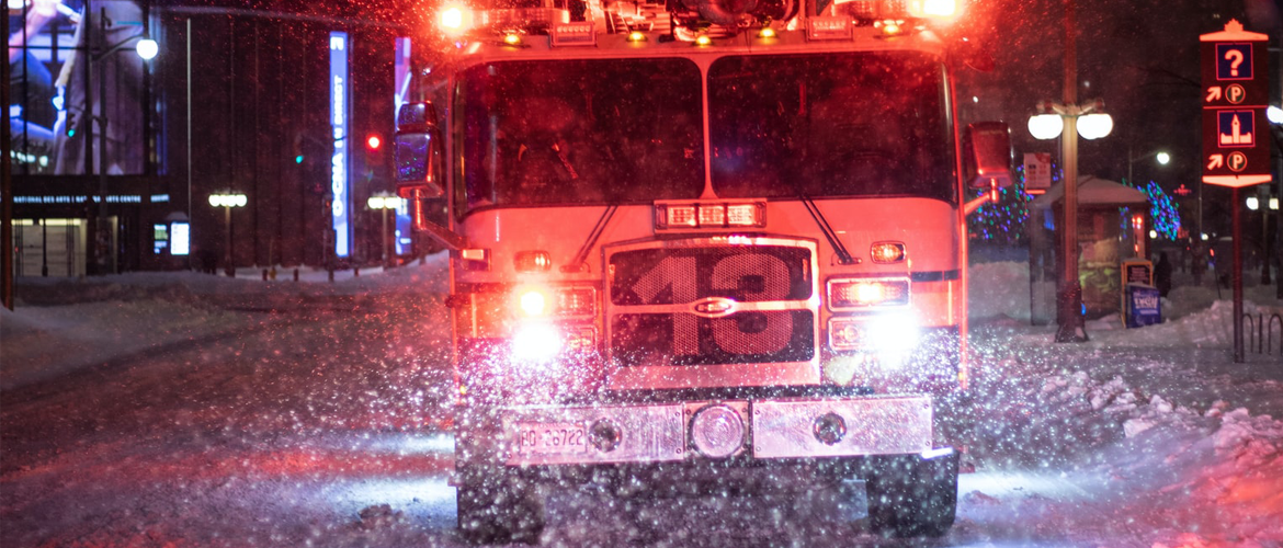 A fireturck driving down the road in the snow.